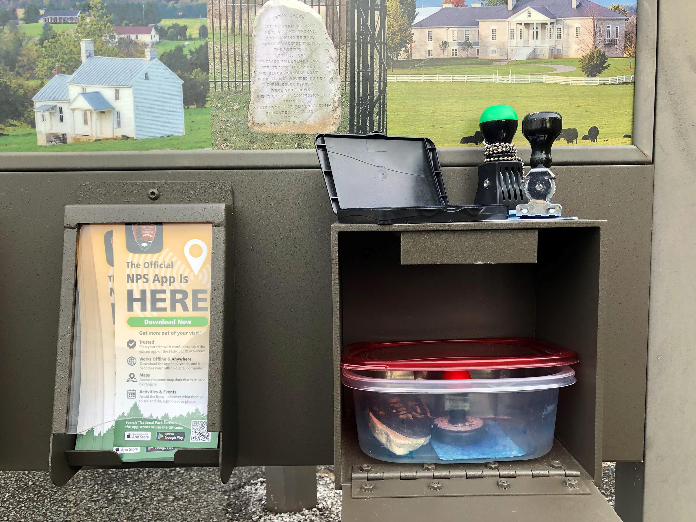 Ink stampers and an ink pad sit atop an open compartment in an information kiosk.
