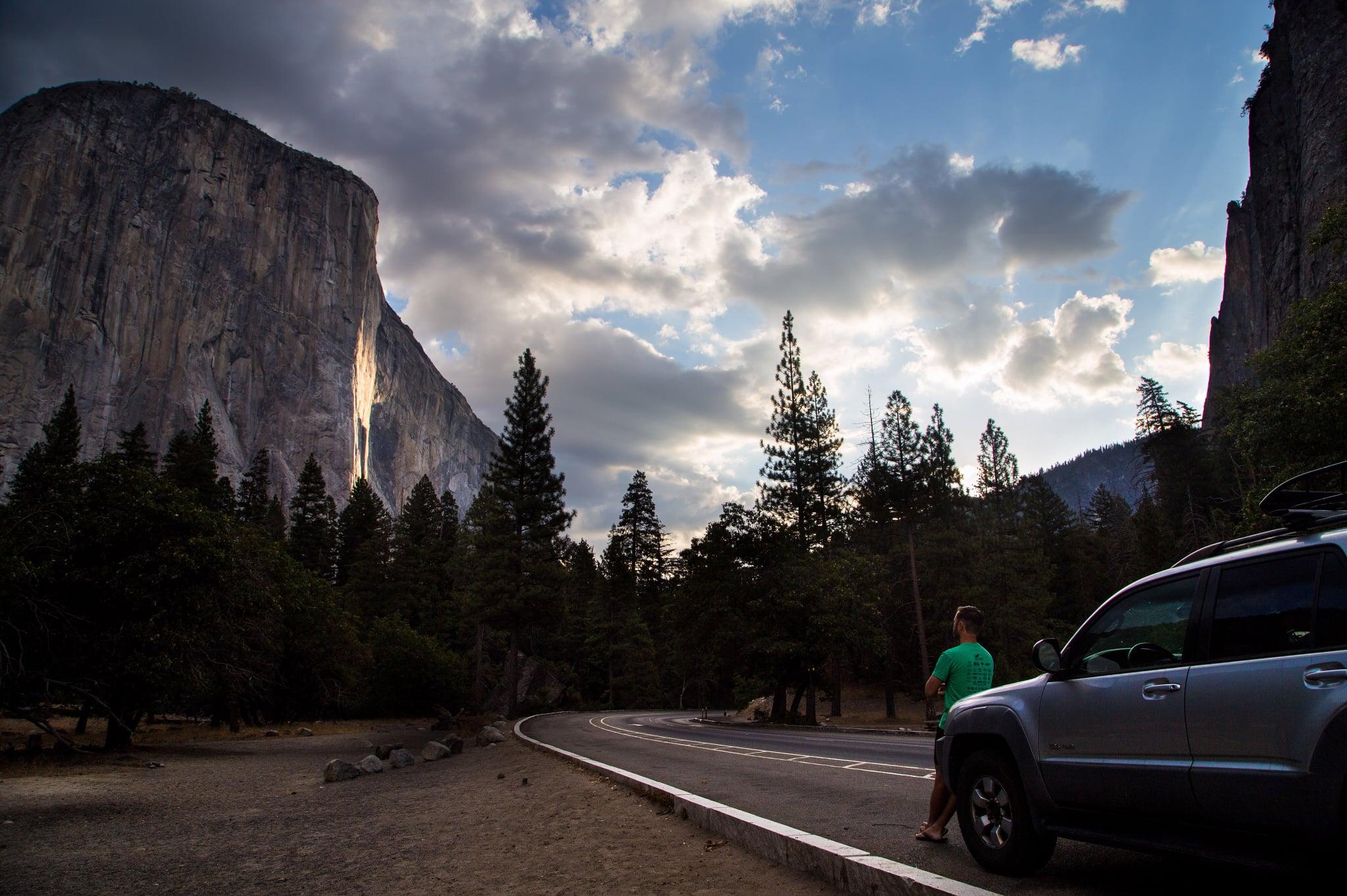 Car parked along Bridalveil Straight with El Capitan in view and a person leaning on the hood