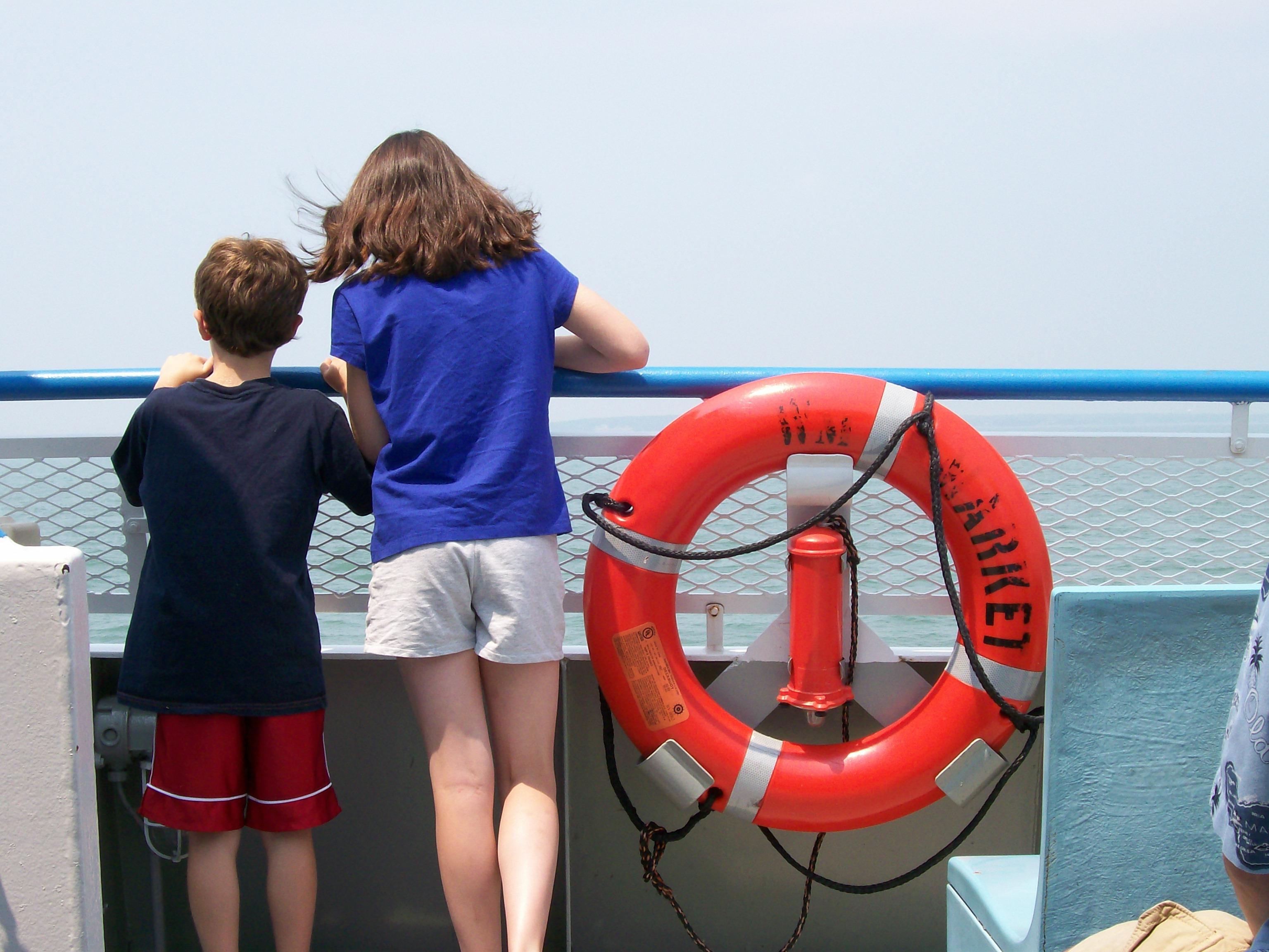 two youth leaning on the gunwale of a boat looking at a broad river