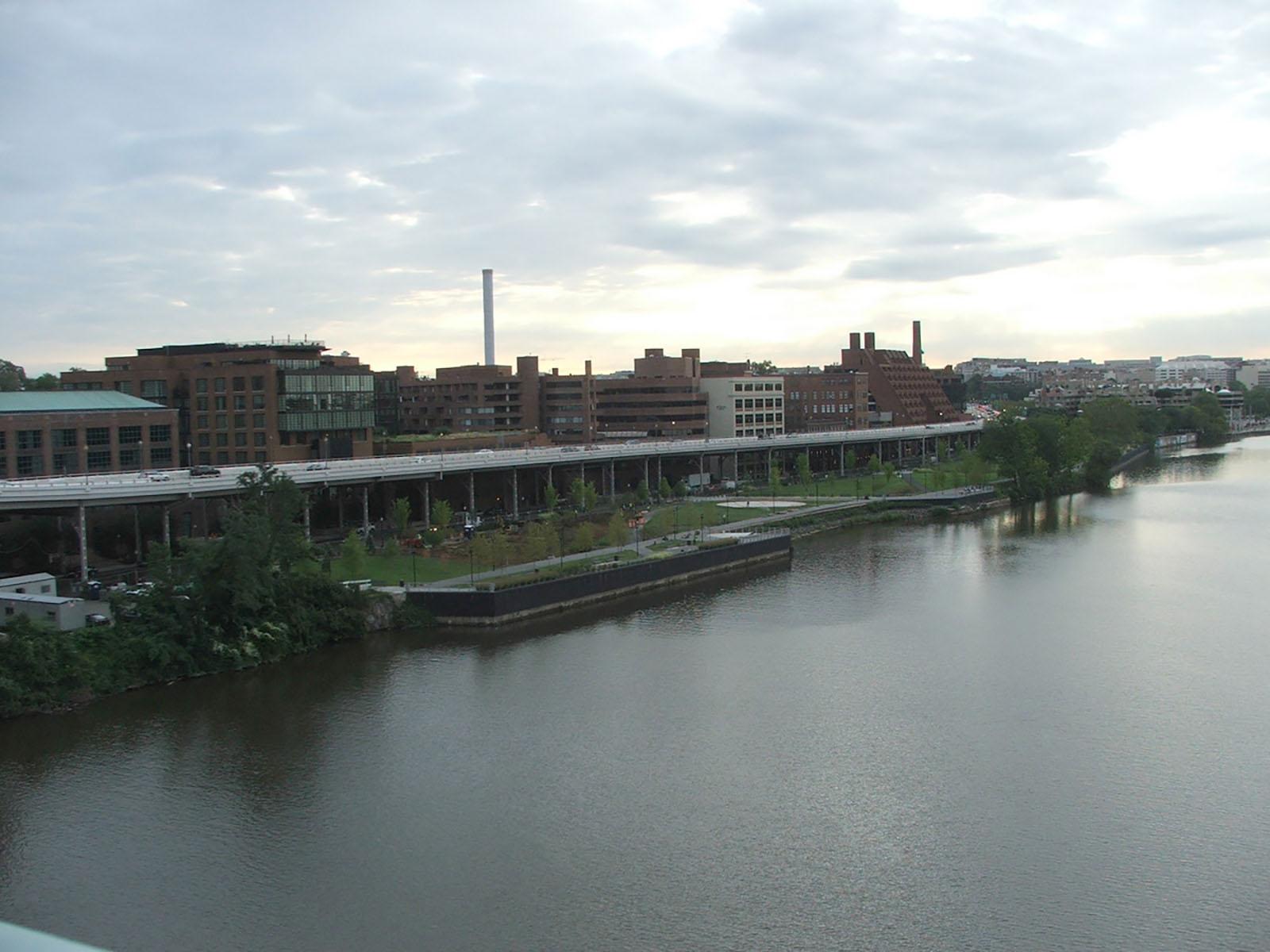 River, park and city skyline below a cloudy sky