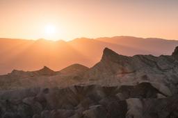 badlands bathed in pale pink and orange light from the setting sun
